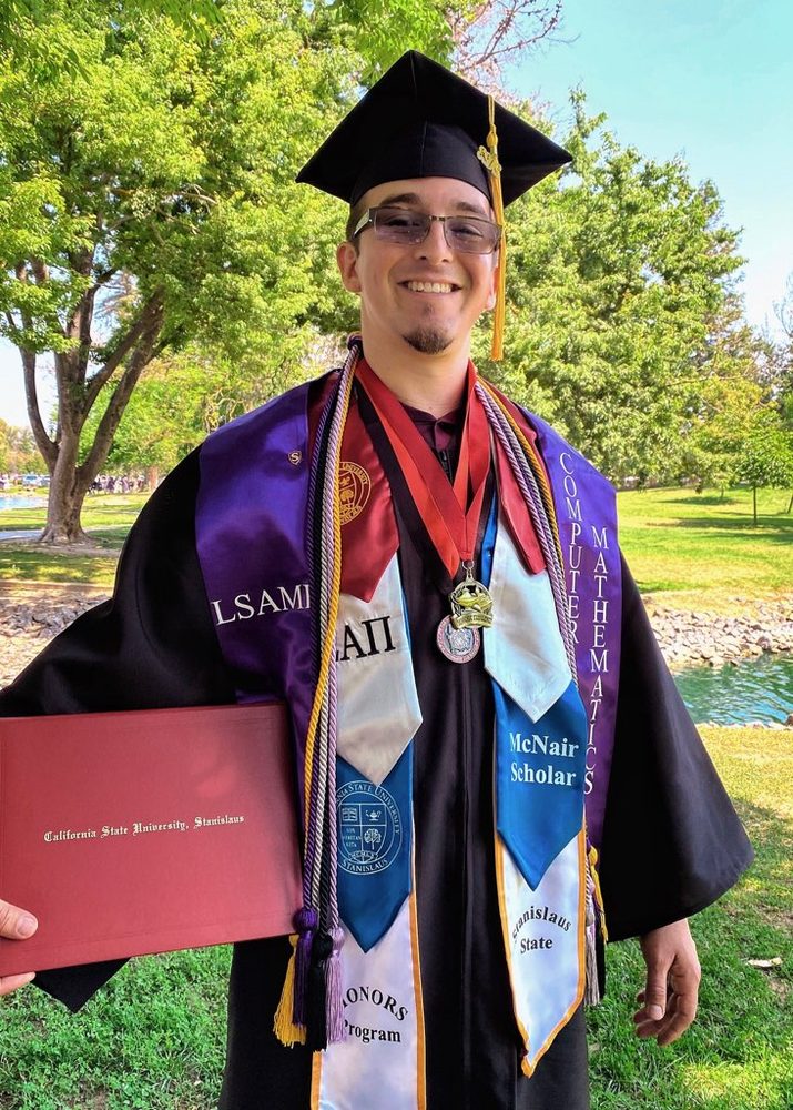 Raymond Dueñas in cap and gown with McNair Scholar and LSAMP stoles at his CSU Stanislaus graduation